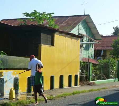 residential street of colorful houses, a man cleaning a wall and boy walking