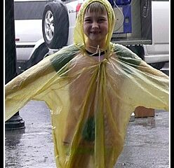 Little girl wearing yellow rain poncho in rain