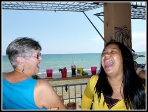 2 women laughing in restaurant with view of ocean