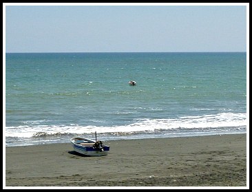 Blue sky, ocean, and a small fishing boat on the sand