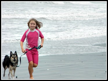 girl running on beach with her dog