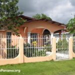 Tan cement house with fence and yard