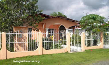 Tan cement house with fence and yard