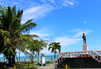 Blue sky, statue, palm trees, railings of a waterfront park