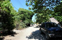 photo of dirt road with car parked and 3 people walking in distance