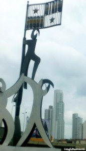 metal statue of 3 figures climbing a flag pole, Panama flag on top