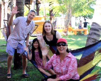 Photo of 2 adults & 2 kids on or by a hammock