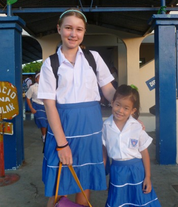 2 young girls, one white, one Chinese, in school uniforms
