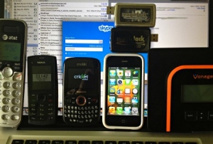 Various telephone in front of computer screen with Skype showing