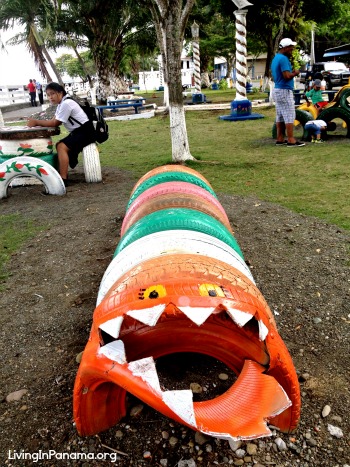 A row of tires 1/3 in the grond and painted too look like a mult-colored catepillar with teeth
