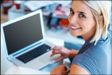 Woman on laptop, looking over shoulder at camera