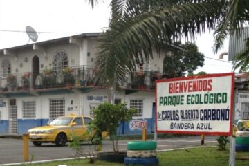 White building with balcony, sign of park, and street scene