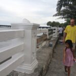 man and young girl walking and looking at cement rail being built