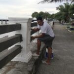 Man painting new cement railings white