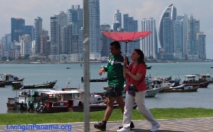 Couple walking along waterfront in Panama City with broken umbrella