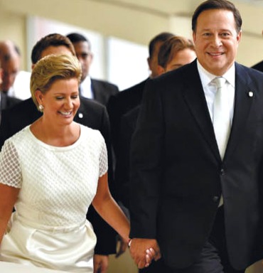 First lady, in white dress, and President Varela in suit holding hands