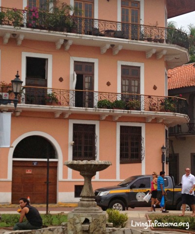 Peach colored building with balconies and people on street