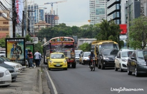 Street in Panama City with buses, cars, motorcycle, and pedestrians