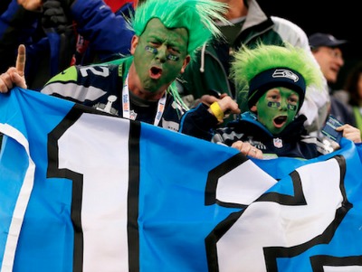 2 seahawks fans with green hair and face holding a big number 12 banner