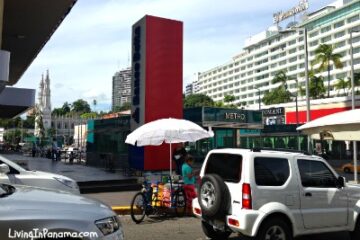 Congested city corner with a son-cone vender, metro station, cars, buildings