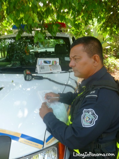 Panama policeofficier writing a ticket on the front of his car, radar gun in view