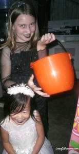 2 girls in halloween custumes one holding an orange pumpkin bucket