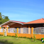 An brown adobe house with tile roof against a blue sky