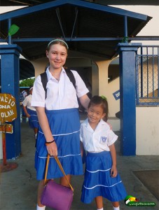 2 girls in school uniforms standing in front of school