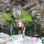 Man and daughter on boulders by river