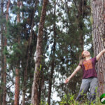 girl posing in front of pine trees