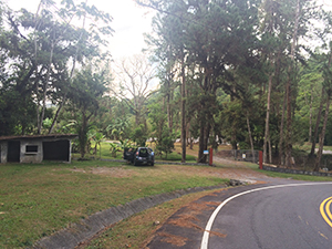 road curing to right and grassy area with a ruin and car parked on left