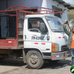 Building supply delivery truck with driver standing in front of it.