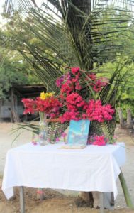 a handmade station of the cross with table, flowers, palm leaves, bible, and image of jesus on cross