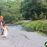 two girls walking on a hill of grave with river and trees beyond