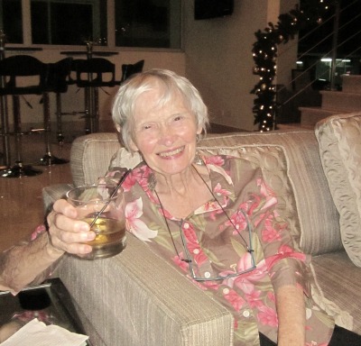 old woman sitting on couch with drink in her hand