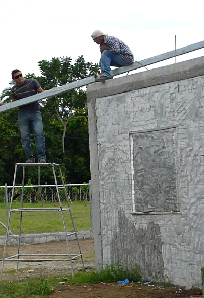 2 men using M2 panels and cement to build a house 