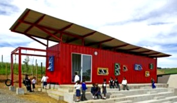 red shipping container with elavated sloping roof and windows