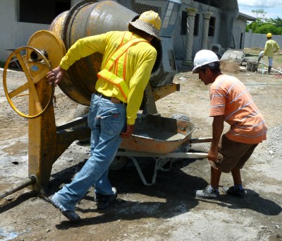 2 men working a cement mixer at building site