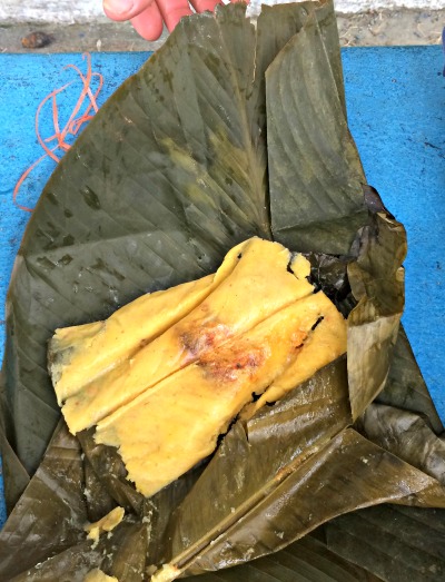 tamale sitting open on the leaves it was cooked in
