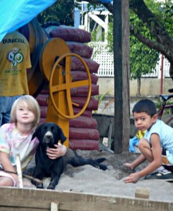 2 children and a dog with bags of cement, sand, and cement mixer
