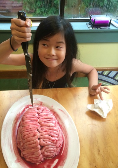 young girl with a big knife and a brain cake