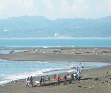 fishing boat being launched from shore with 10 men