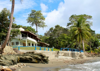 light yellow building with balconies on a green lawn and on ocean front