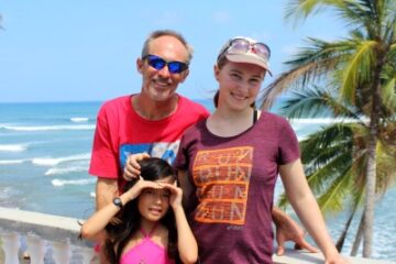 man and 2 daughters with ocean and palm tree backdrop