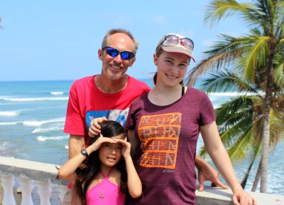 man and 2 daughters with ocean and palm tree backdrop