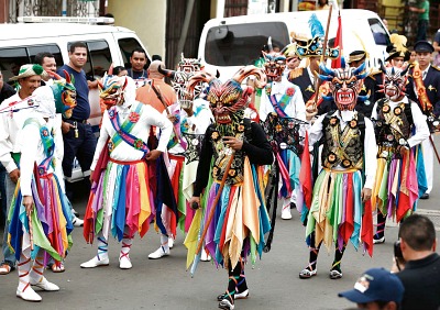 parade of people with colorful devilesque costumes