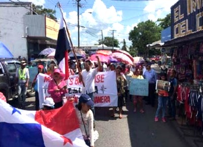 people in a protest march with signs and Panama flags