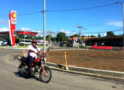 photo of motorcycle going around traffic circle in front of gas station