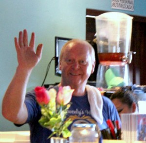 middle-aged man waving behind bar