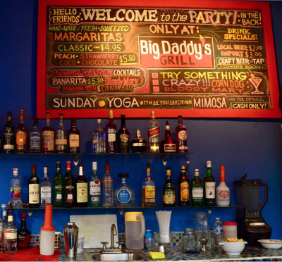 colorful menu chalkboard over bar full of liquor bottles